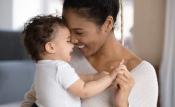 Mother holding infant and smiling together