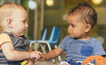 Infants holding hands in a childcare classroom