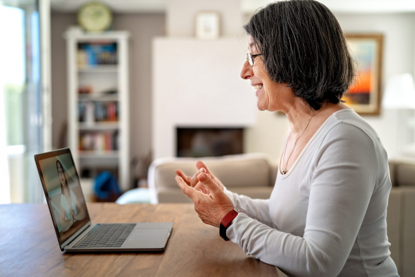 Adult woman having video chat online on laptop with her granddaughter at home during quarantine isolation pandemic. Senior lifestyle. Teacher giving online lesson to student from home.