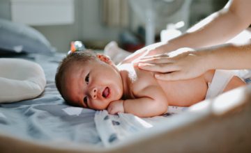 hands touch back of newborn