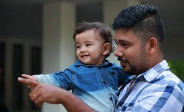 Father holding son and both are pointing to the left