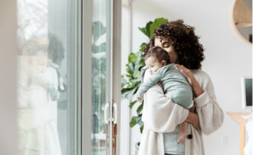 mom holds baby by window